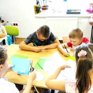 Dzieci rysują oraz wycinają kształty z kolorowego papieru