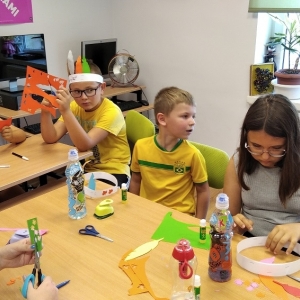 Dzieci wycinają i przyklejają elementy z kolorowego papieru