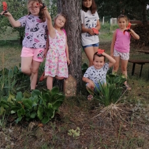 Dzieci stojąc w pobliżu drzewa prezentują swoje prace