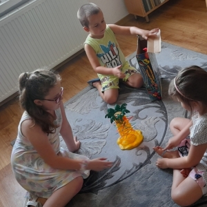 Dzieci siedzą obok stojącej na dywanie gry