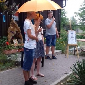 Mężczyzna stoi w pobliżu kobiety która trzyma parasol razem z innym mężczyzną