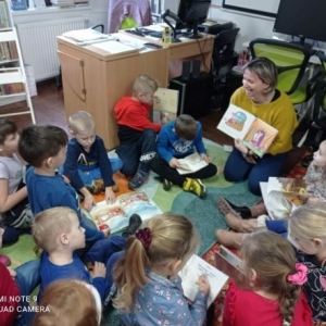Kobieta pokazuje dzieciom ilustracje w książce