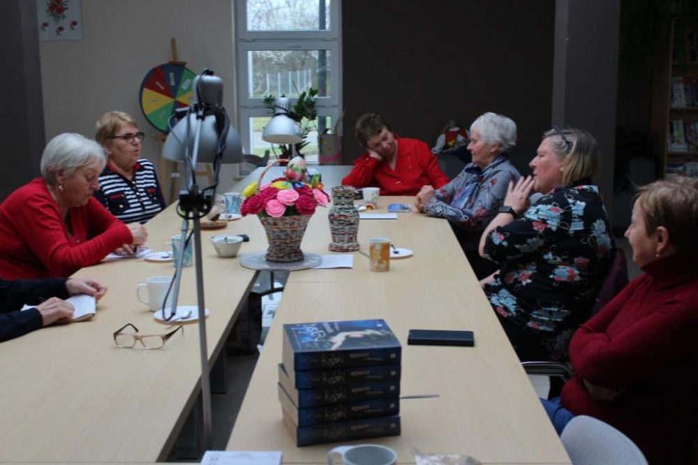 Uczestnicy kwietniowego spotkania DKK siedzą do okoła stołu i rozmawiają